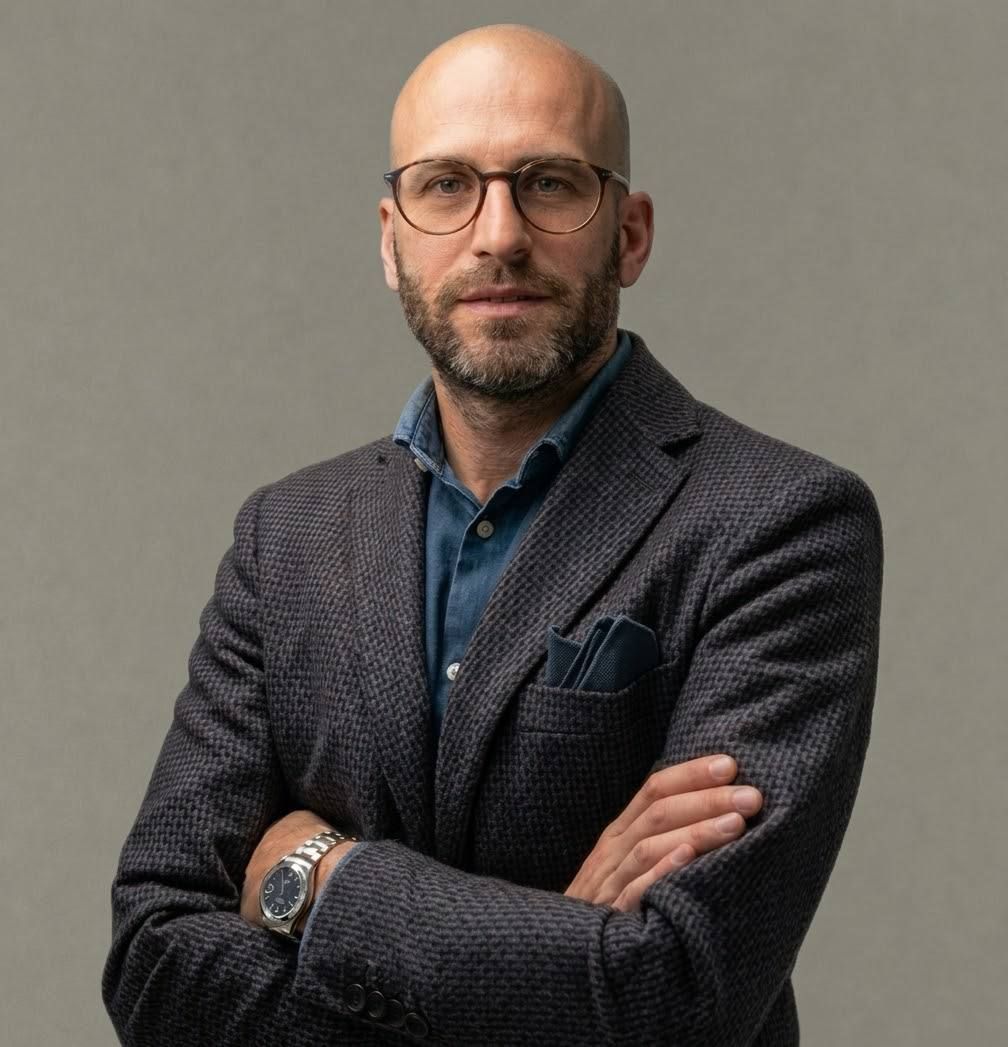 Foto a mezzo busto professionale di Carlo Apostoli, giacca grigia, camicia blu, sfondo grigio